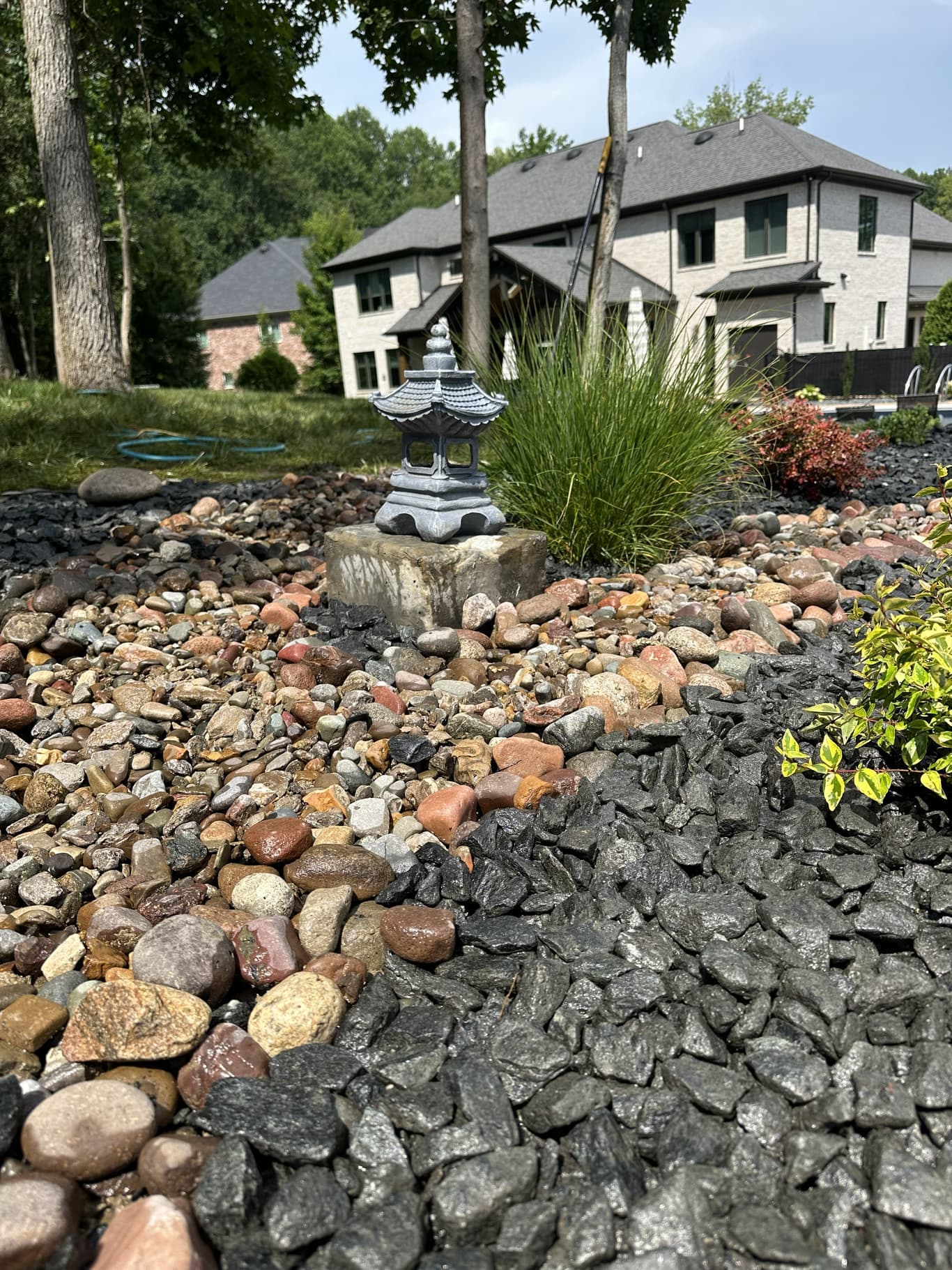A tidy ornamental garden bed with grasses, shrubs, and a stone lantern set in decorative rock, maintained by Horizon Outdoor Solutions in Owensboro, KY